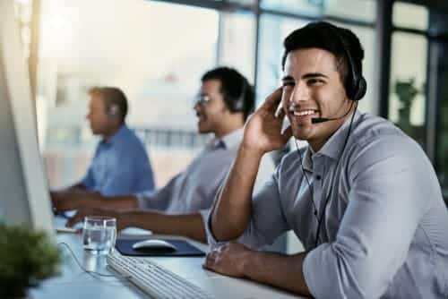 Cropped shot of a call centre agent working in an office with his colleagues in the background