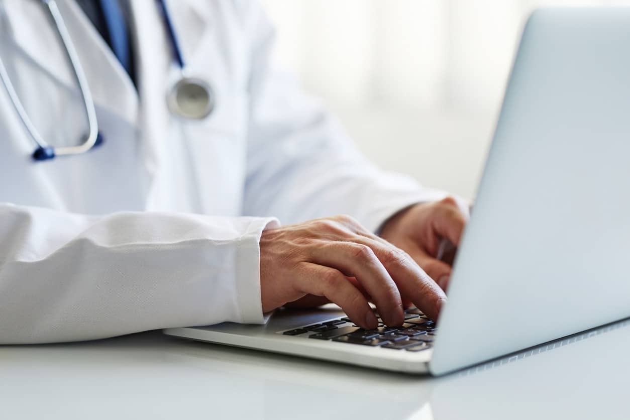 Male doctor working on laptop at clinic
