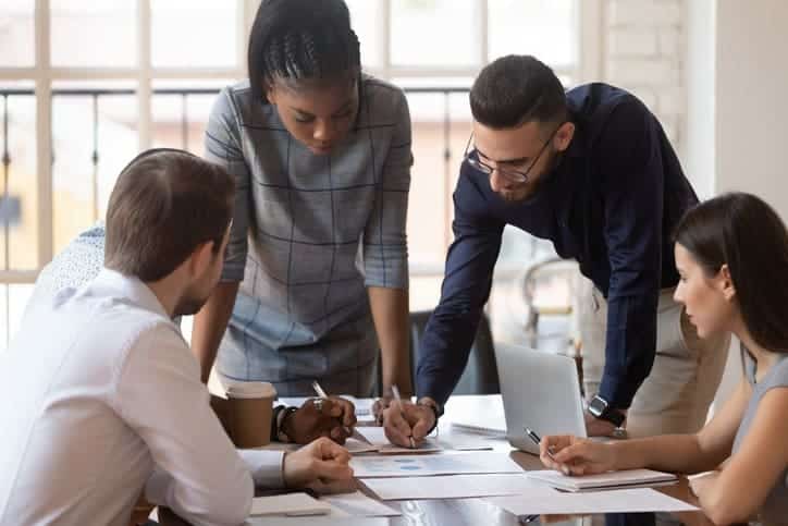 group of consultants:Focused multiracial corporate business team people brainstorm on marketing plan financial report gather at office table meeting, diverse serious colleagues group discuss paperwork engaged in teamwork