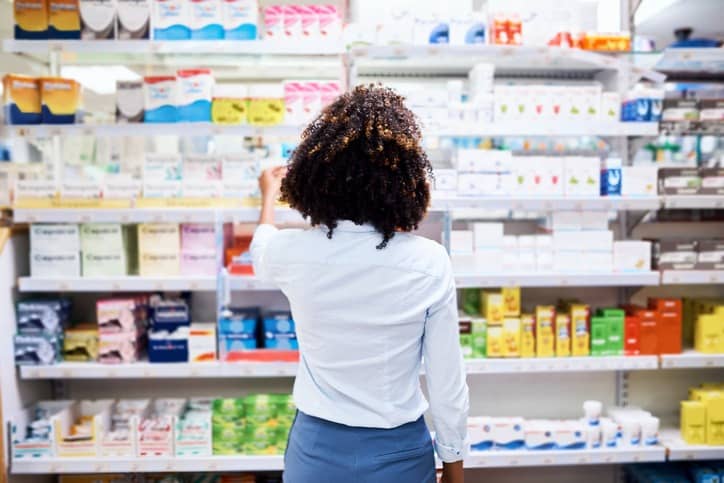 How to Revitalize Patient Centricity in Pharma: Rearview shot of a young woman looking at products in a pharmacy