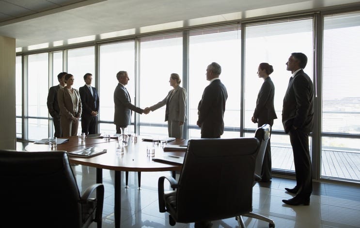 Leveraging Salesforce for Community Bank Mergers and Acquisitions: Business people shaking hands in conference room