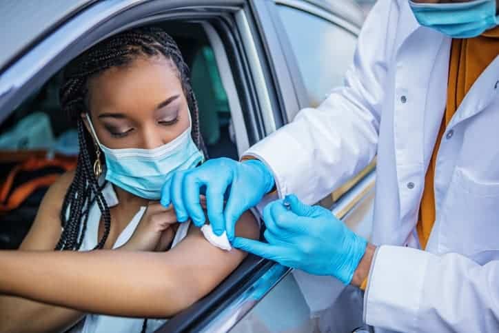Covid-19 Vaccination administered by a black doctor at a drive-in medical facility