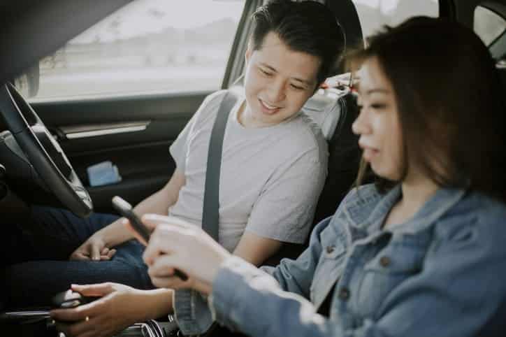 young couple checking phone in car