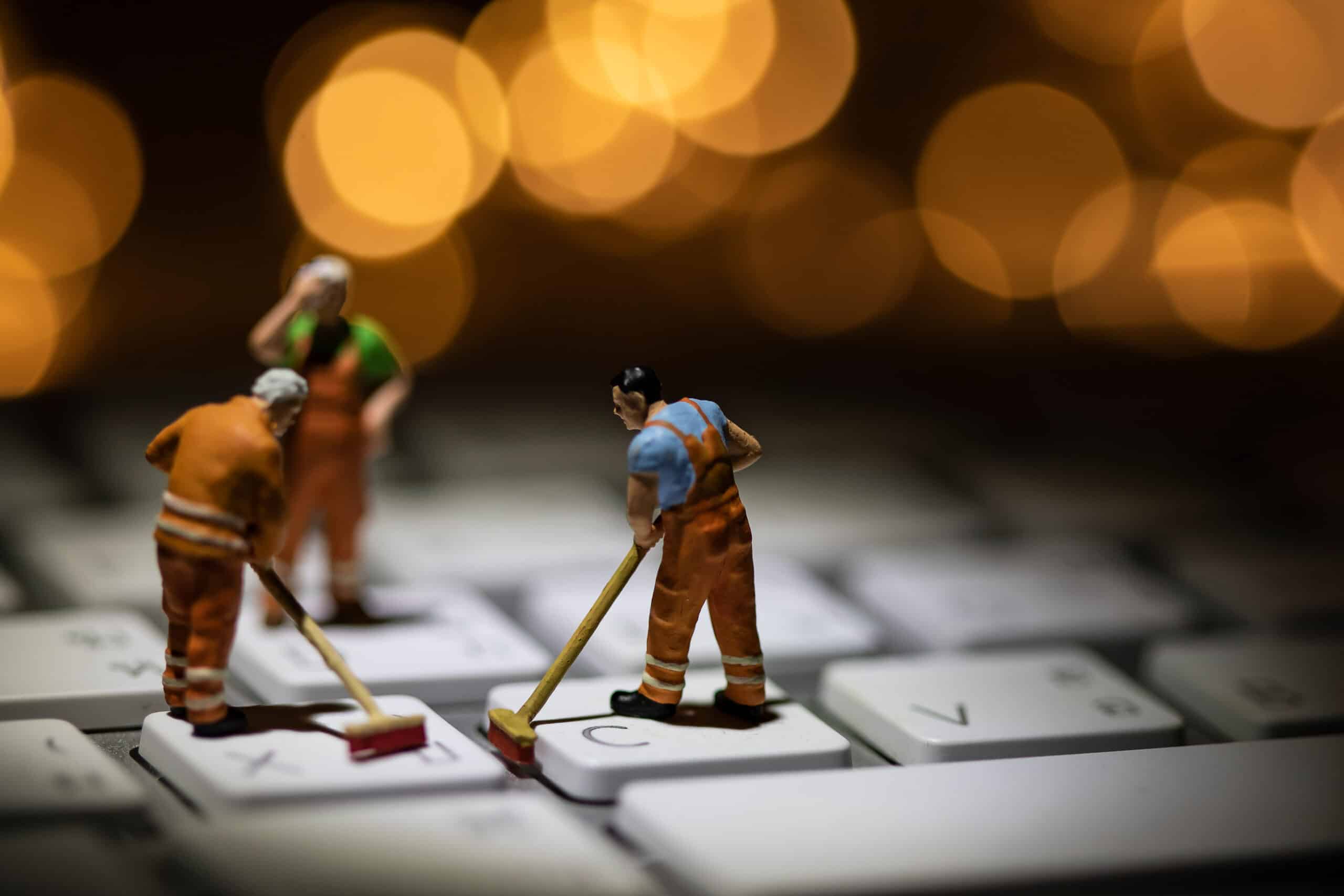 Small janitor figurines cleaning a keyboard